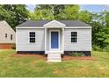 Charming single-story home featuring gray siding, a blue front door and a well-maintained lawn at 518 Avon Ave, Burlington, NC 27215