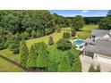 Aerial view of a pristine backyard showcasing a pool, lush greenery, mature trees, and ample lawn space at 60 Hartwood Ln, Youngsville, NC 27596