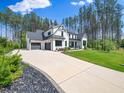 Eye-catching home with a long driveway, lush lawn, and black and white modern design at 604 Dappled Pine Ave, Durham, NC 27713