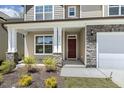 Inviting front porch with stone accents, a mahogany front door, and meticulously landscaped garden at 605 Hampton Crest Ct, Fuquay Varina, NC 27526