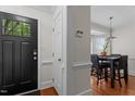 Inviting entryway features a black front door with glass panes and hardwood floors, offering a glimpse into the dining area at 6904 Sandringham Dr, Raleigh, NC 27613