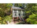 Charming two-story home with light green siding, black shutters, and landscaped front yard, nestled within mature trees at 6904 Sandringham Dr, Raleigh, NC 27613