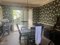 Dining room with a chandelier and a glass-top table surrounded by dark wallpapered walls at 713 Beddingfield Dr, Knightdale, NC 27545