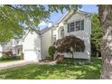 Two-story home with white siding, an attached garage, and beautiful front yard landscaping at 8721 Springhouse Ln, Raleigh, NC 27617