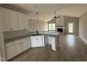 Modern kitchen featuring white cabinets, granite countertops, stainless steel appliances, and views of a gas fireplace at 94 Royal Ave, Selma, NC 27576