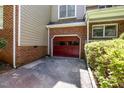Close-up of a red garage door framed by brickwork and surrounded by lush greenery at 1015 Boathouse Ct, Raleigh, NC 27615