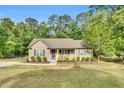Charming single-story home featuring a cozy front porch, manicured landscaping, and a lush, wooded backdrop at 114 Cherryhill Dr, Four Oaks, NC 27524