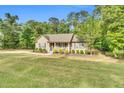 Welcoming single-story home with a lush green lawn, mature trees, and a cozy front porch, creating a serene setting at 114 Cherryhill Dr, Four Oaks, NC 27524