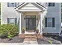 Elegant front door with decorative glass, framed by white columns and brick steps with planters at 24 W Canterbury Ct, Wendell, NC 27591