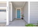 Charming covered front porch with light gray siding, white trim, and a vibrant turquoise front door at 3313 Brunot St, New Hill, NC 27562
