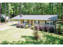 Inviting single-story home with a metal roof, covered carport, and landscaped yard, nestled among mature trees at 4221 River Run Dr, Sanford, NC 27332