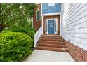 Charming brick entryway featuring a blue front door with sidelights and a white railing at 5416 Whisperwood Dr, Durham, NC 27713