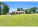 Charming brick ranch-style home with a large front yard and extended driveway leading to a garage at 585 Cokesbury Rd, Fuquay Varina, NC 27526