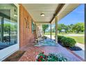 Welcoming front porch with rocking chairs, decorative tile flooring, and colorful flower accents at 585 Cokesbury Rd, Fuquay Varina, NC 27526