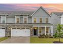 Exterior of a two-story townhome with stone accents, well-maintained lawn, and inviting porch seating at 646 Shelford Trl, Zebulon, NC 27597