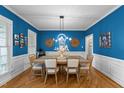 Elegant dining room with bright blue walls, wainscoting, and a modern chandelier over the wooden table at 905 Neuse Ridge Dr, Clayton, NC 27527