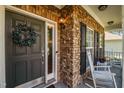 Close-up of a stone-accented front porch with a wreath, rocking chair, and a stylish front door at 1028 Bellenden Dr, Durham, NC 27713
