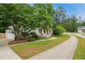 Suburban home featuring a lush front yard, a sidewalk, mature trees, and a charming covered front porch at 1102 Whiston Dr, Apex, NC 27502
