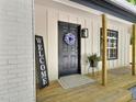 Charming front porch featuring a black door, welcome sign, wood columns, and farmhouse lantern at 116 Lumpkin St, Raleigh, NC 27610