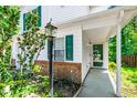 Inviting entrance with a covered porch, green front door, brick accents, and an outdoor light fixture at 12 Byerly Ct, Durham, NC 27713