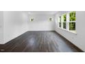 Spacious living room with dark hardwood floors and multiple windows letting in natural light and a view of the backyard at 174 Hickory Grove Dr, Sanford, NC 27330