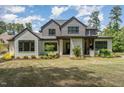 A backyard featuring a covered patio with an outdoor kitchen, fireplace, and beautifully landscaped lawn at 2016 Falls Forest Dr, Raleigh, NC 27615