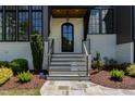 Inviting front entrance features a glass door, gray stone steps, black railings and lush landscaping at 2016 Falls Forest Dr, Raleigh, NC 27615