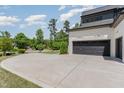 Spacious concrete driveway leading to a two-car garage with black doors, surrounded by green trees at 2016 Falls Forest Dr, Raleigh, NC 27615