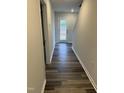 Hallway with dark wood-look floors leading to a white door with view of wooded area at 2118 Terrawood Dr, Durham, NC 27703