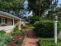 Brick walkway leading to home surrounded by mature trees and lush landscaping at 2143 Ridge Rd, Raleigh, NC 27607