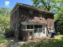 The back of a brick home shows its enclosed back porch and the property's yard at 404 Kinsey St, Raleigh, NC 27603