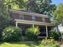 Two-story brick home featuring a large front porch with white columns, surrounded by lush greenery at 404 Kinsey St, Raleigh, NC 27603