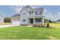 Inviting two-story home featuring a covered front porch and attached two-car garage at 48 Sanders Farm Dr, Smithfield, NC 27577