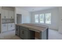 Spacious kitchen area featuring a large gray island and white cabinets, flooded with natural light from three windows at 48 Sanders Farm Dr, Smithfield, NC 27577