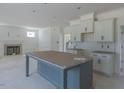 Open-concept kitchen with a gray island, white cabinets, and tile backsplash flows into the living area with a fireplace at 48 Sanders Farm Dr, Smithfield, NC 27577