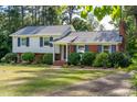Charming two-story home features a blend of siding and brick, complemented by dark shutters and lush landscaping at 4813 Glen Forest Dr, Raleigh, NC 27612