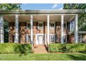 Brick house featuring white columns, black shutters, and a lush green lawn at 5513 Parkwood Dr, Raleigh, NC 27612