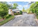 A brick home with a two-car garage and a spacious driveway surrounded by trees at 5513 Parkwood Dr, Raleigh, NC 27612