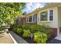 Inviting home exterior featuring brick accents, mature bushes, and well-manicured landscaping at 5517 Spring Rd, Raleigh, NC 27603
