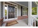 Close up of a black paneled front door with sidelights and a 'Welcome' mat on a brick porch at 606 Churton Grove Blvd, Hillsborough, NC 27278
