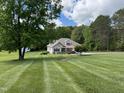 Charming one-story home with manicured lawn, two-car garage, and a lush wooded backdrop at 84 Macbeth Ln, Roxboro, NC 27574