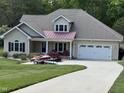 Charming one-story home with manicured lawn, two-car garage, and front porch with chairs and a jet ski at 84 Macbeth Ln, Roxboro, NC 27574