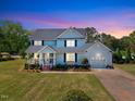 Charming two-story home with attached garage, well-manicured lawn, and inviting front porch at dusk at 128 Christy Ln, Dunn, NC 28334