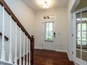 Bright foyer with hardwood floors, a staircase with white railings, and a glass-paneled door providing natural light at 1314 Cornell Pl, Raleigh, NC 27607