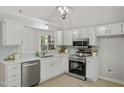 Modern kitchen featuring stainless steel appliances, sleek white cabinets, and light blue backsplash at 20 Meadowcrest Dr, Durham, NC 27703
