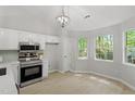 Bright eat-in kitchen featuring stainless steel appliances, white cabinets, and hardwood floors at 20 Meadowcrest Dr, Durham, NC 27703