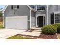 Inviting entrance with a black front door, gray siding, and manicured landscaping at 204 Trevor Ridge Dr, Holly Springs, NC 27540