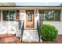 Inviting front entrance with a wood door, manicured shrubbery, and freshly painted white brick facade at 2712 Nc 57, Hillsborough, NC 27278