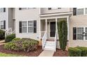 Close-up of the front entrance featuring a black door, white trim, and manicured shrubs at 407 Whitehall Ct, Clayton, NC 27520