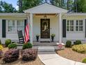Inviting front porch with rocking chair, American flag, and well-maintained landscaping at 4112 Huckleberry Dr, Raleigh, NC 27612